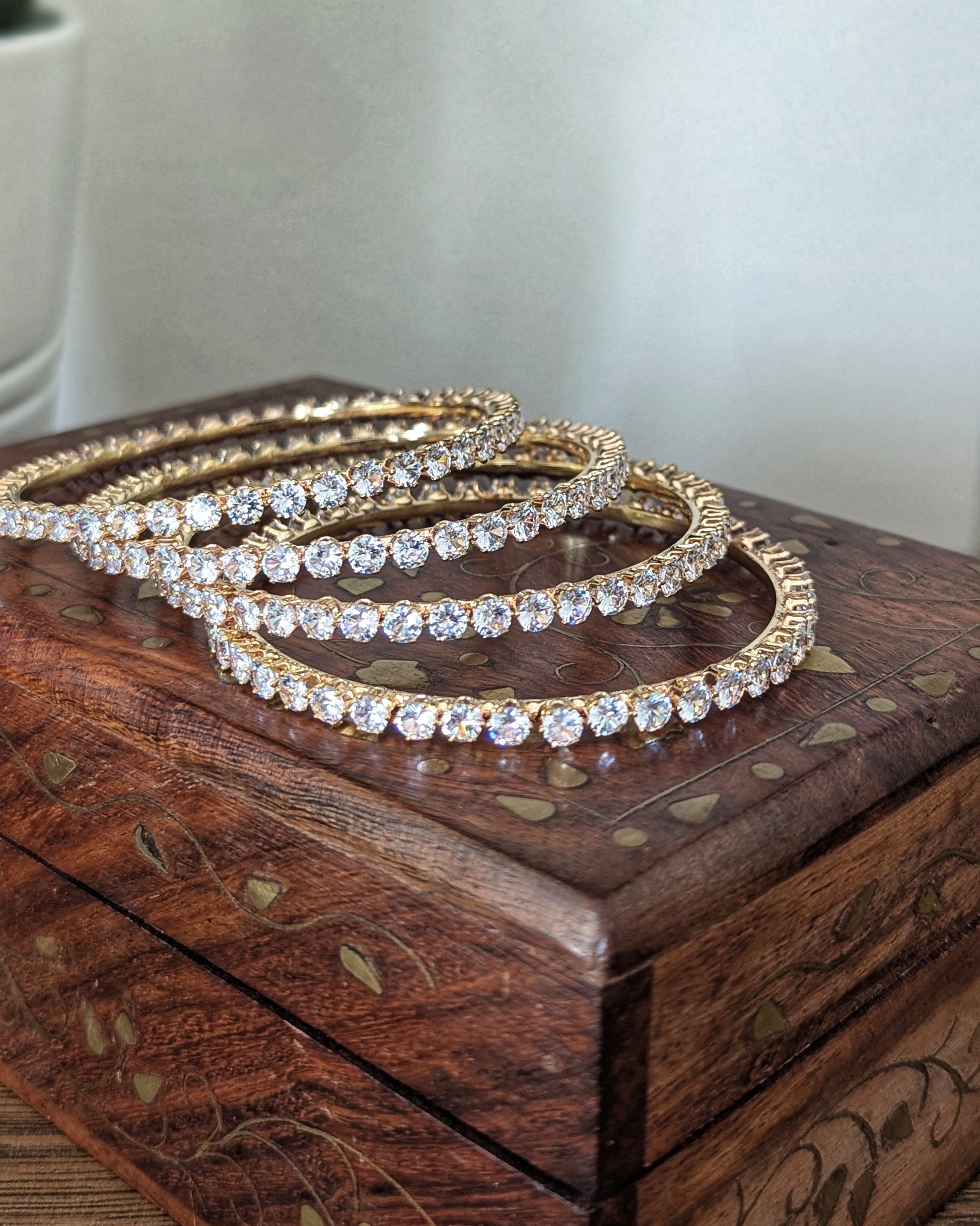 A set of four slim, gold-plated imitation bangles with a minimalist design and subtle sparkle. The bangles are stacked together on a soft fabric background, showcasing an everyday elegant style available at @sufnacanada. Pick-up in Ajax Ontario. Worldwide shipping available. Perfect for wedding, festival jewelry, indian Jewelry, kids jewelry, kundan jewelry, gifting, costume jewelry, fashion jewelry, Eid, onam, Diwali, karwachauth,