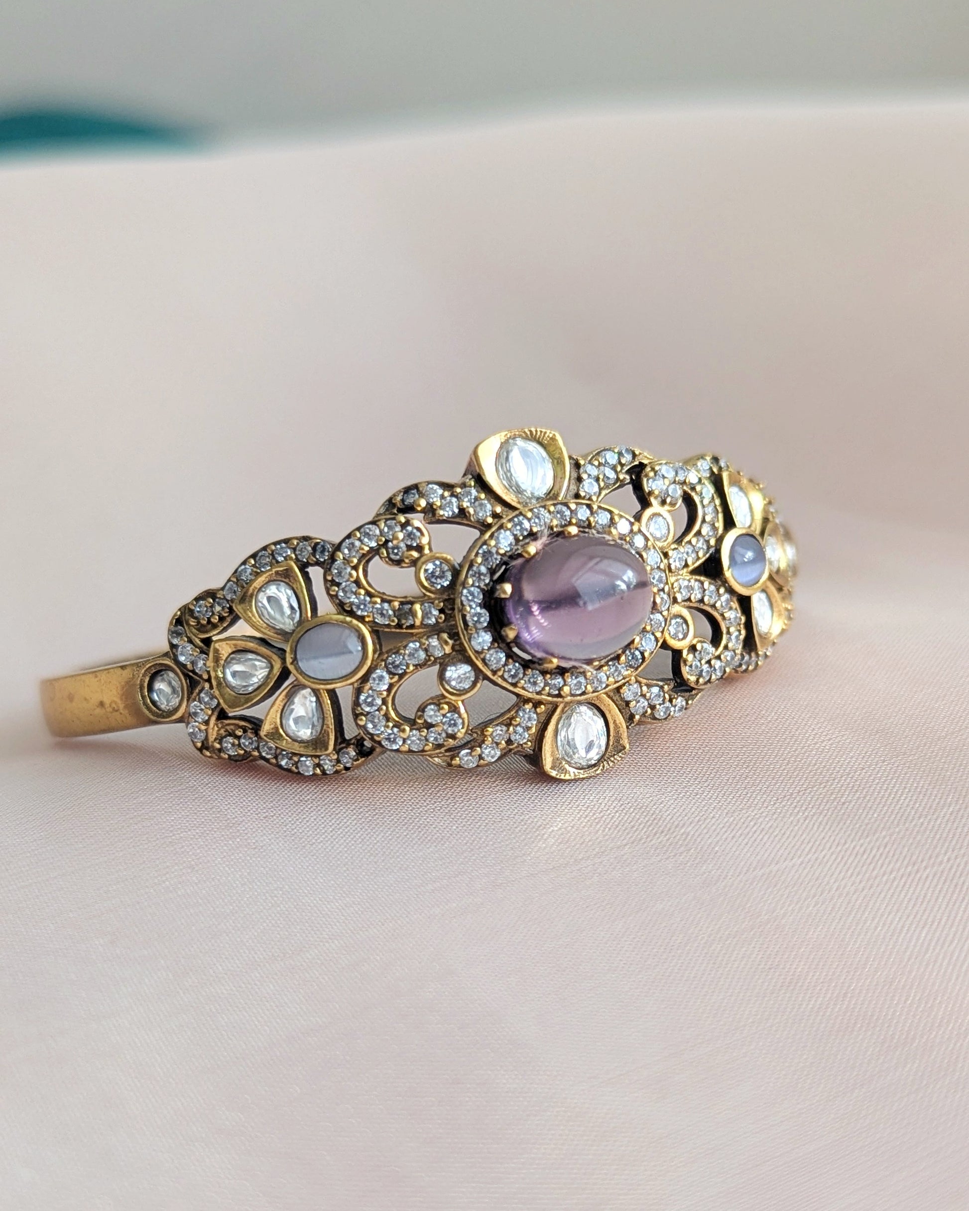 Single Bangle with purple gemstone and gold accents on a soft fabric background. Pick-up in Ajax Ontario. Worldwide shipping available. Perfect for wedding, festival jewelry, indian Jewelry, kids jewelry, kundan jewelry, gifting, costume jewelry, fashion jewelry, Eid, onam, Diwali, karwachauth, navratri. Free shipping available. Jewelry for women. Indian jewelry in ajax durham region. Bollywood style jewelry.