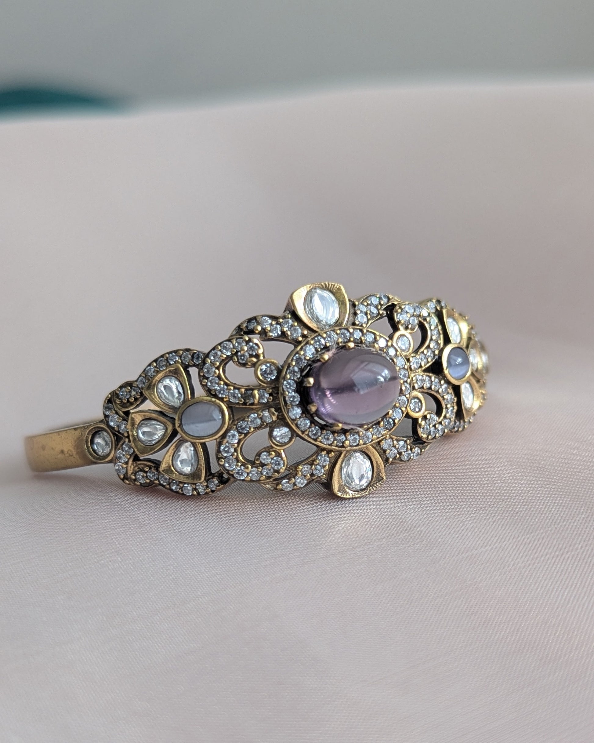 Single Bangle with purple gemstone and gold accents on a soft fabric background. Pick-up in Ajax Ontario. Worldwide shipping available. Perfect for wedding, festival jewelry, indian Jewelry, kids jewelry, kundan jewelry, gifting, costume jewelry, fashion jewelry, Eid, onam, Diwali, karwachauth, navratri. Free shipping available. Jewelry for women. Indian jewelry in ajax durham region. Bollywood style jewelry.