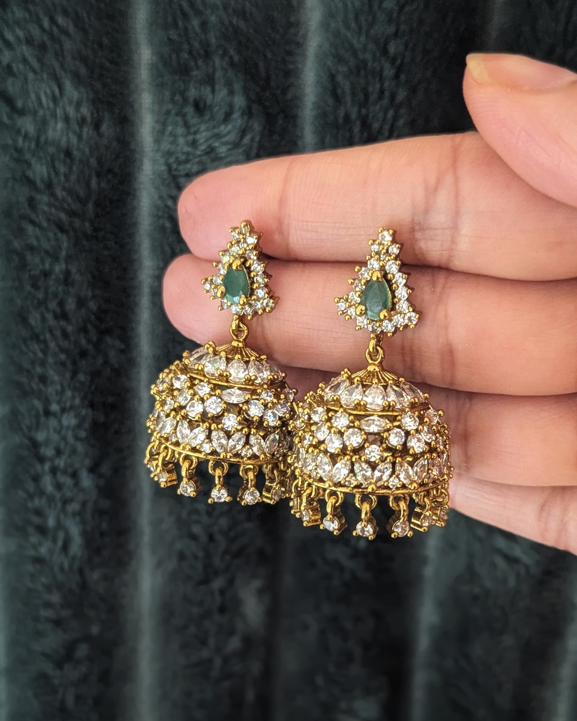 Gold and green gemstone earrings held by a hand on a light background looks like real gold. Pick-up in Ajax Ontario. Worldwide shipping available. Perfect for wedding, festival jewelry, indian Jewelry, kids jewelry, kundan jewelry, gifting, costume jewelry, fashion jewelry, Eid, onam, Diwali, karwachauth, navratri. Free shipping available. Jewelry for women. Indian jewelry in ajax durham region. Bollywood style jewelry.