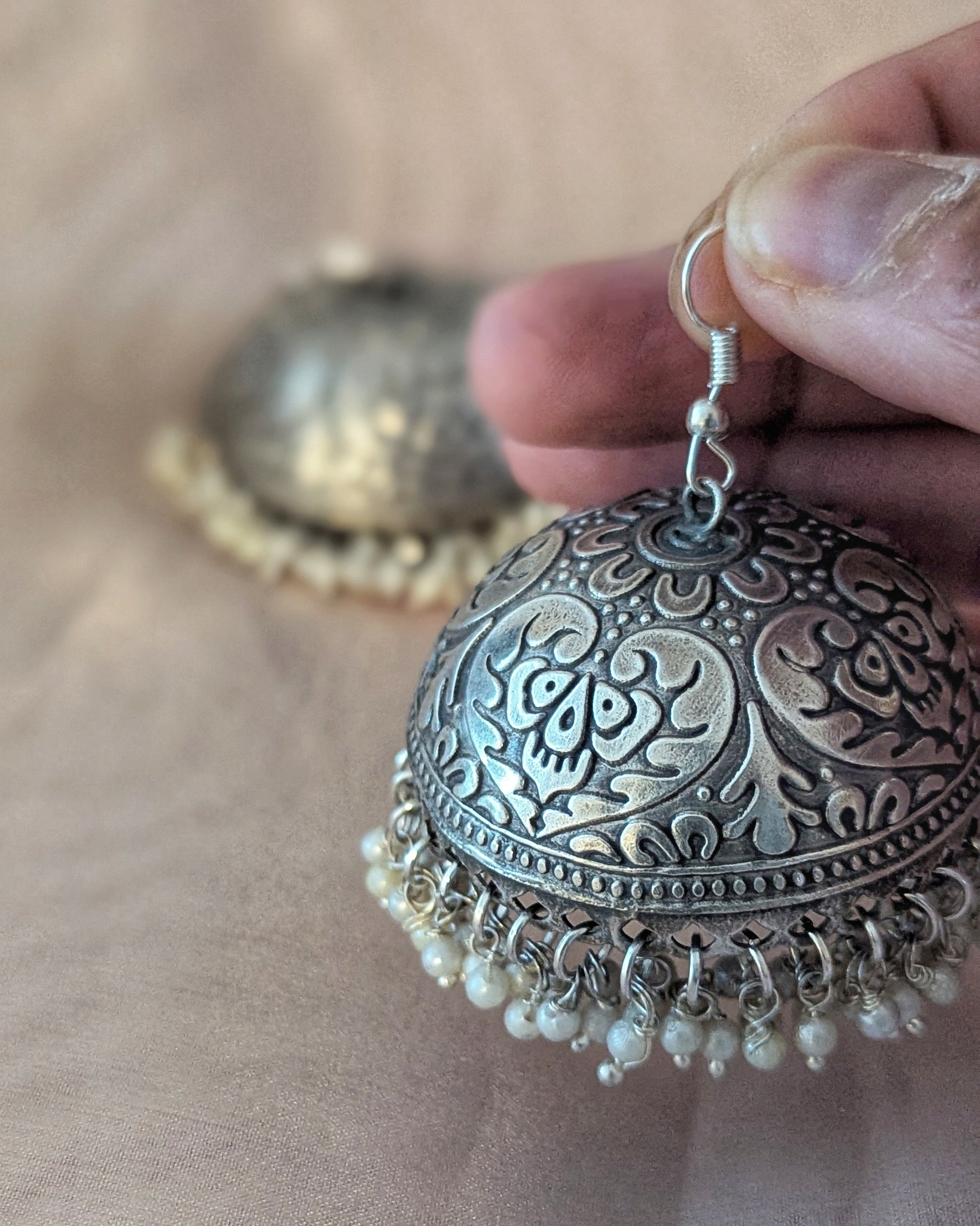 Silver earrings with intricate designs and pearl-like beads on a wooden surface. Pick-up in Ajax Ontario. Worldwide shipping available. Perfect for wedding, festival jewelry, indian Jewelry, kids jewelry, kundan jewelry, gifting, costume jewelry, fashion jewelry, Eid, onam, Diwali, karwachauth, navratri. Free shipping available. Jewelry for women. Indian jewelry in ajax durham region.