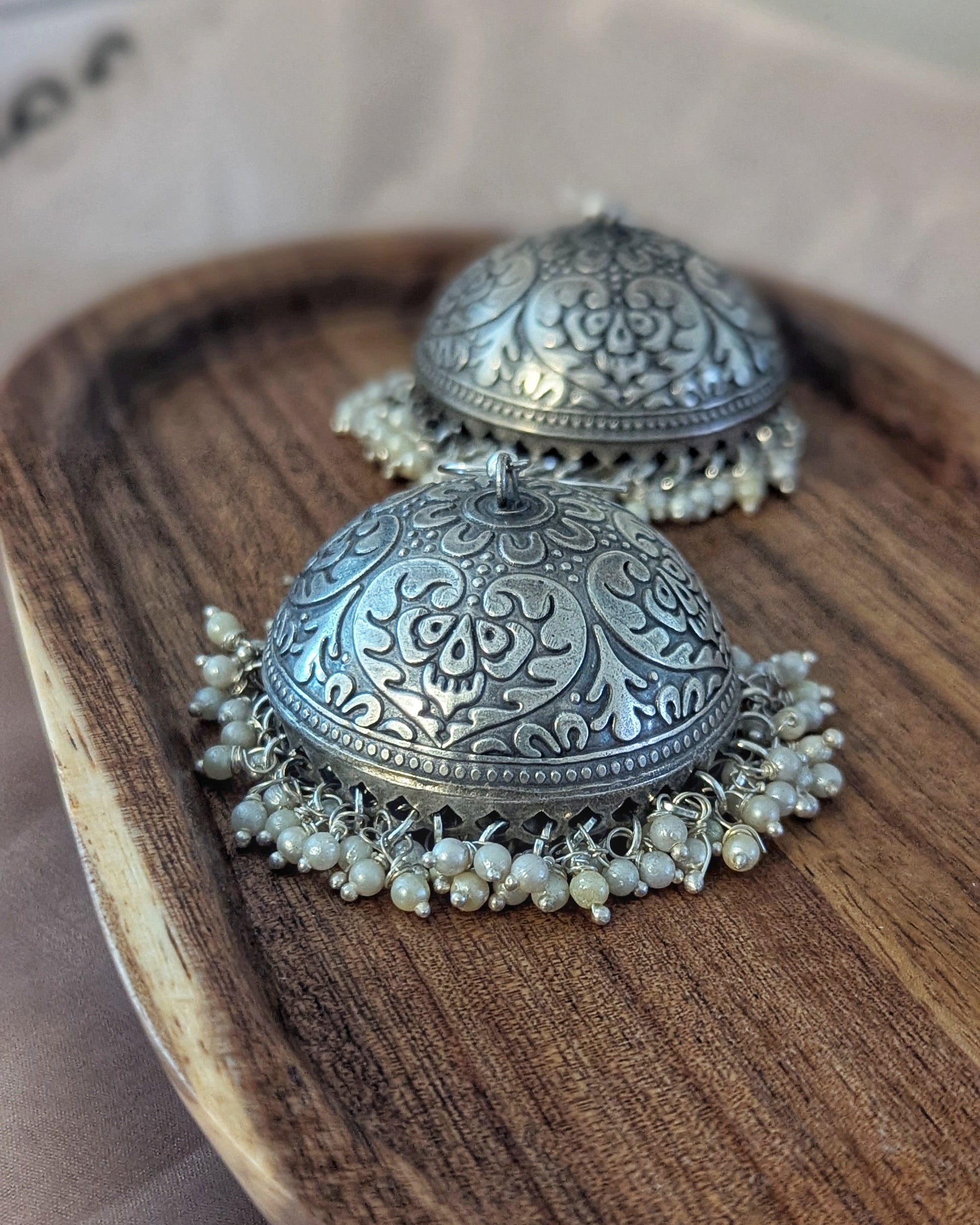Silver earrings with intricate designs and pearl-like beads on a wooden surface. Pick-up in Ajax Ontario. Worldwide shipping available. Perfect for wedding, festival jewelry, indian Jewelry, kids jewelry, kundan jewelry, gifting, costume jewelry, fashion jewelry, Eid, onam, Diwali, karwachauth, navratri. Free shipping available. Jewelry for women. Indian jewelry in ajax durham region.