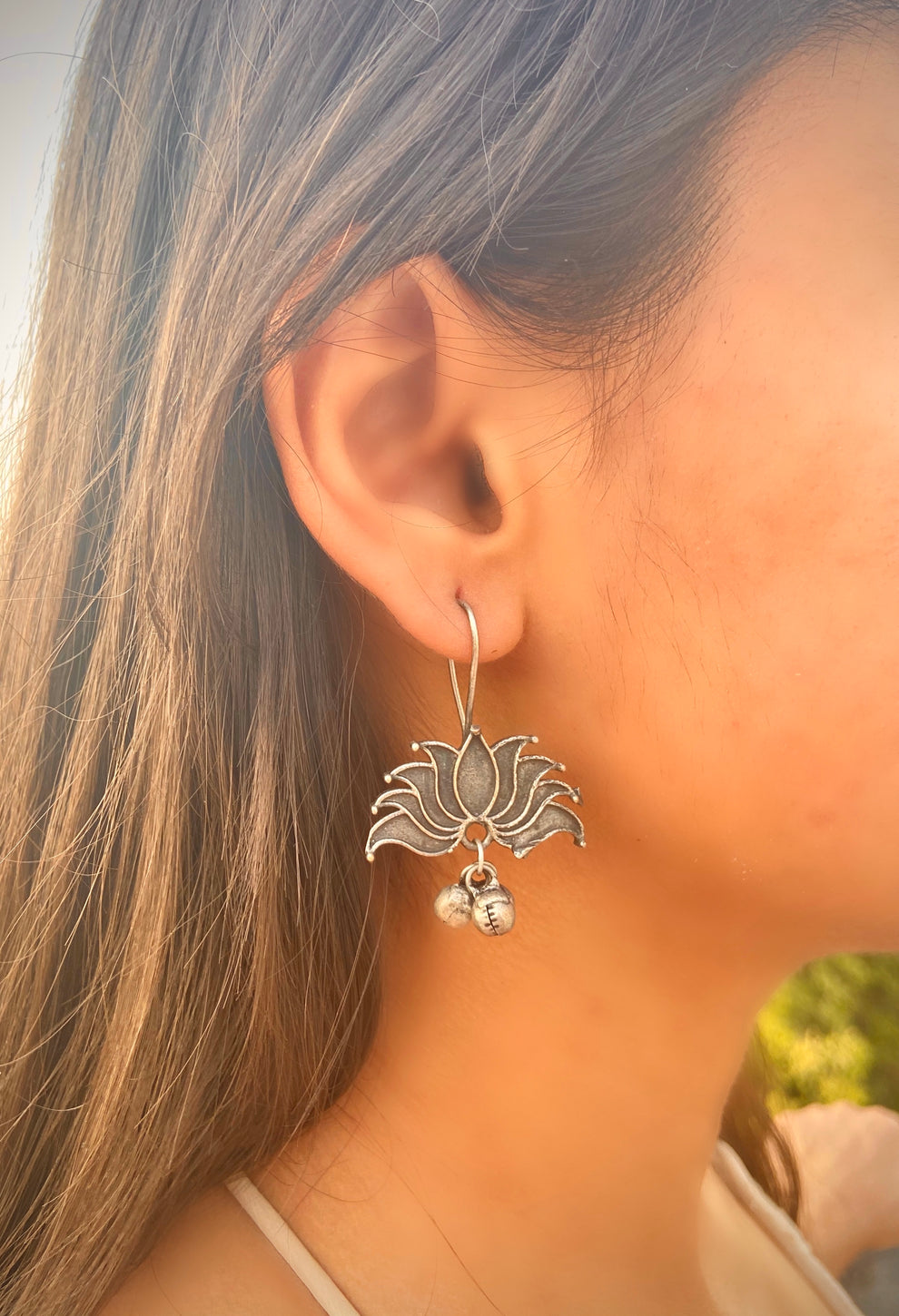 A close-up image of a person wearing a pair of dainty brass earrings in a lotus design. Pick-up in Ajax Ontario. Worldwide shipping available. Perfect for wedding, festival jewelry, indian Jewelry, kids jewelry, kundan jewelry, gifting, costume jewelry, fashion jewelry, Eid, onam, Diwali, karwachauth, navratri. Free shipping available. Jewelry for women. Indian jewelry in ajax durham region.