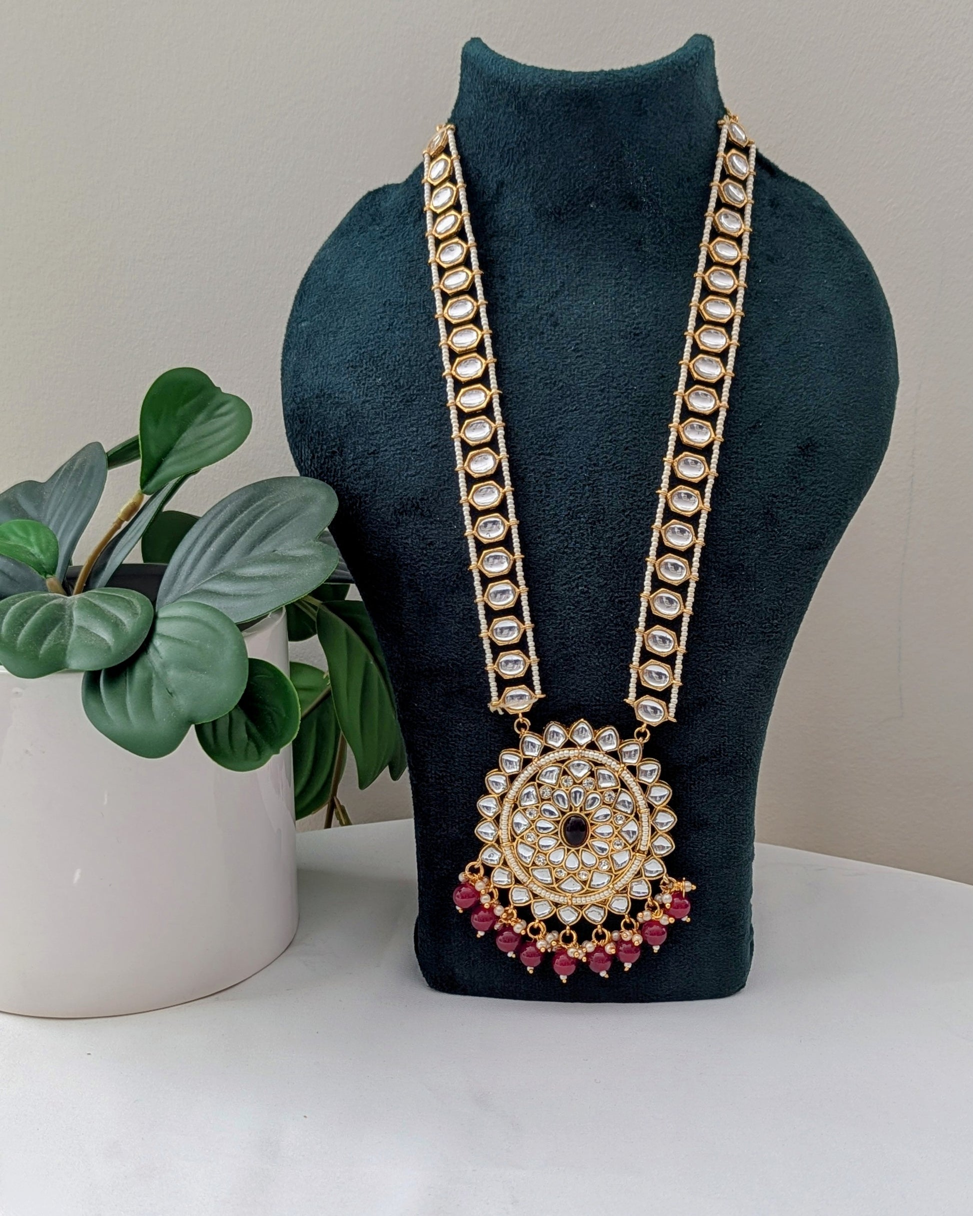 A red kundan necklace with a gold-colored circular pendant and long pearl elements. Available for pickup in Ajax, Ontario and worldwide shipping.