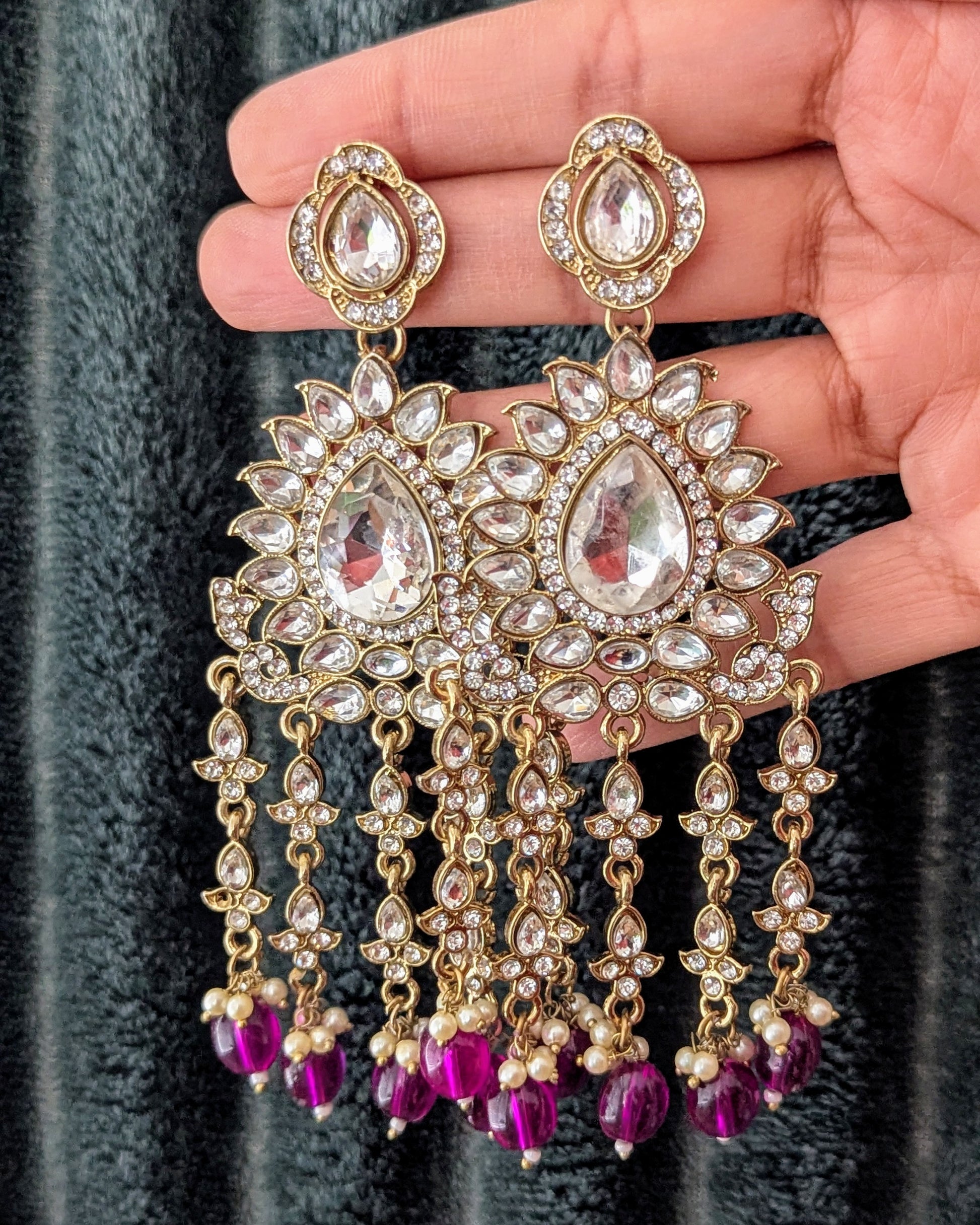 A pair of gold-colored chandbali earrings with purple and white stones, featuring a dangling design. Available for pickup in Ajax, Ontario and worldwide shipping.