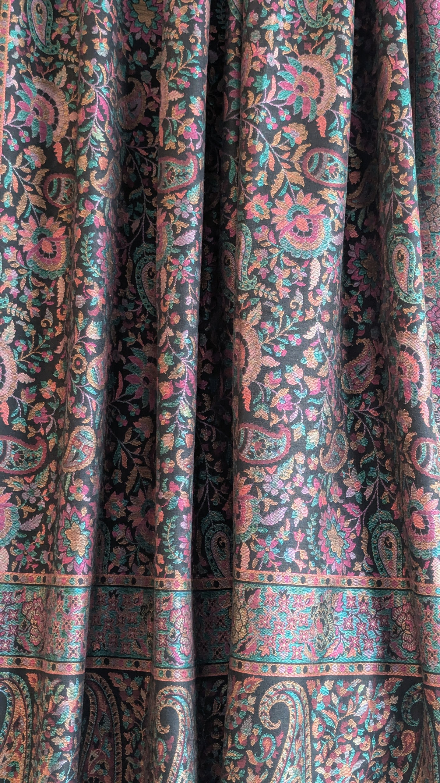 A black Kani lohi with multicolor floral and geometric patterns, displayed on a stand.