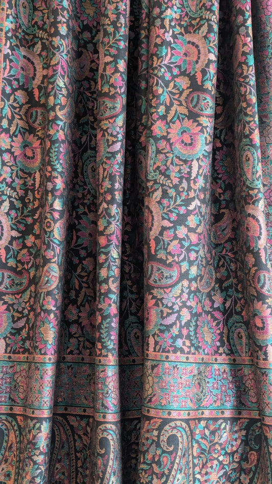 A black Kani lohi with multicolor floral and geometric patterns, displayed on a stand.