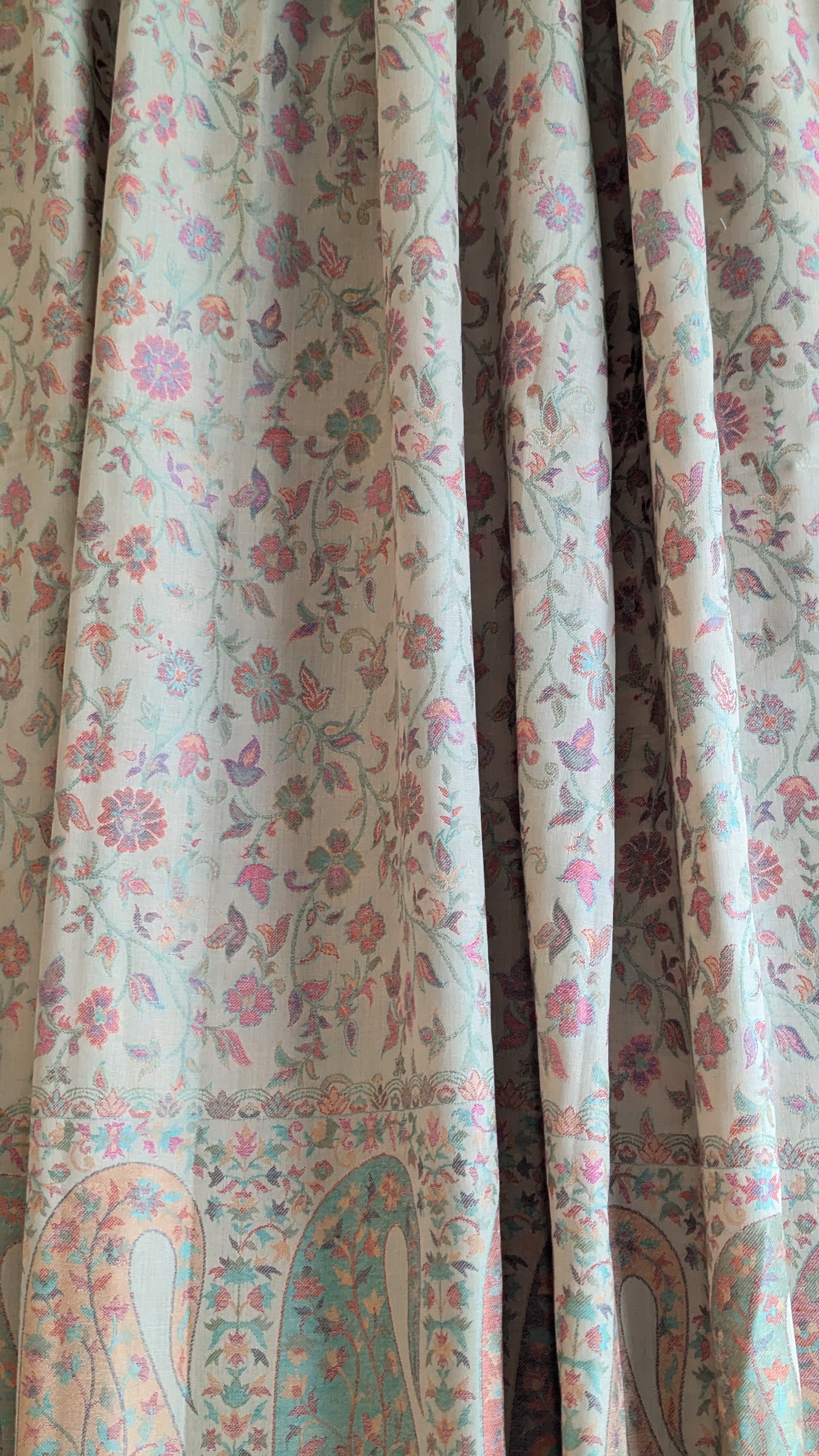 A beige shawl with multicolor patterns displayed.