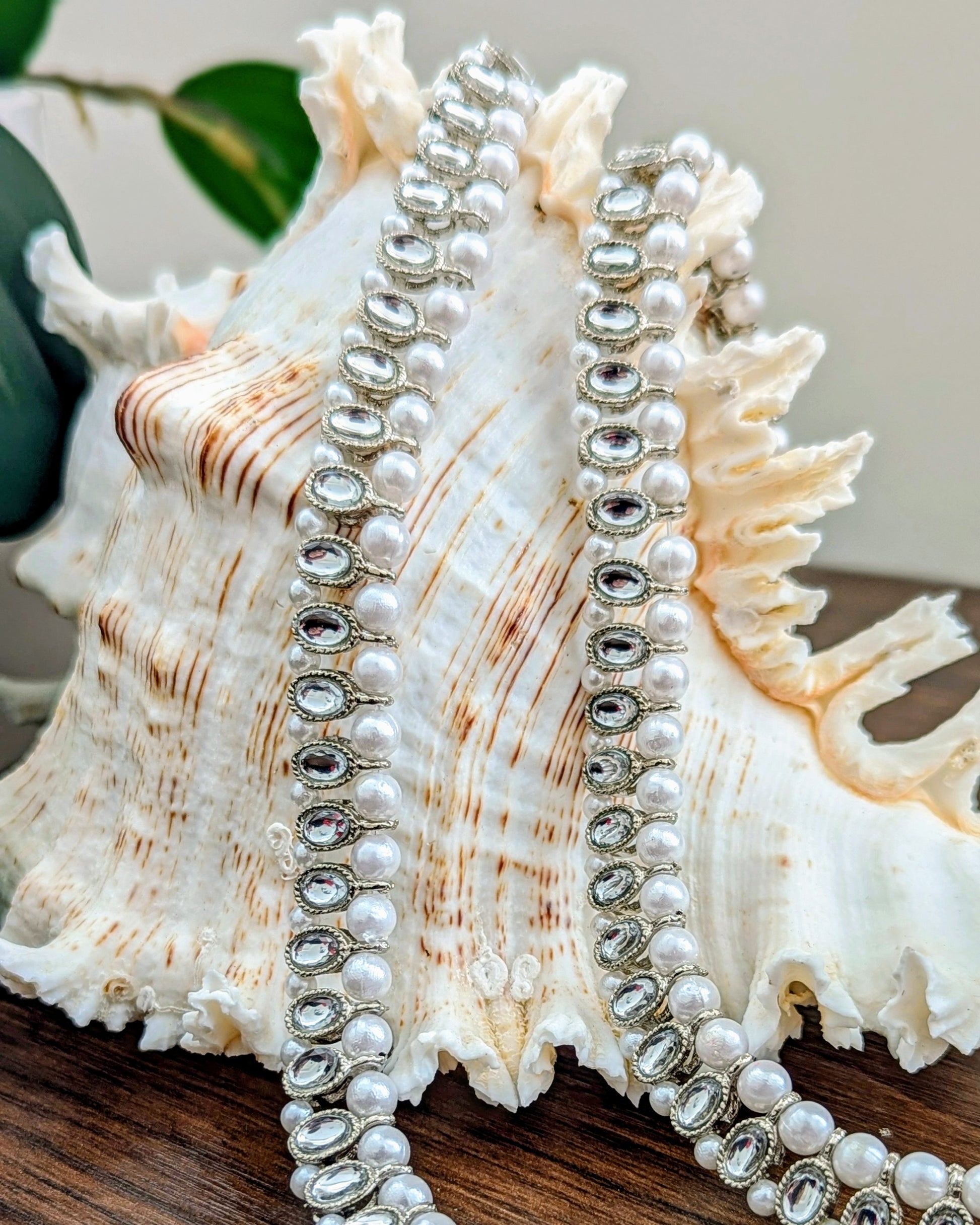 A pair of silver and pearl anklets with zircon stones displayed on a white seashell. Imitation jewelry. Pick-up in Ajax Ontario. Worldwide shipping available. Perfect for weddings, festival jewelry, indian Jewelry, kids jewelry, kundan jewelry, gifting, costume jewelry, fashion jewelry, Eid, onam, Diwali, karwachauth, navratri. Free shipping available. Jewelry for women. Indian jewelry in ajax durham toronto.
