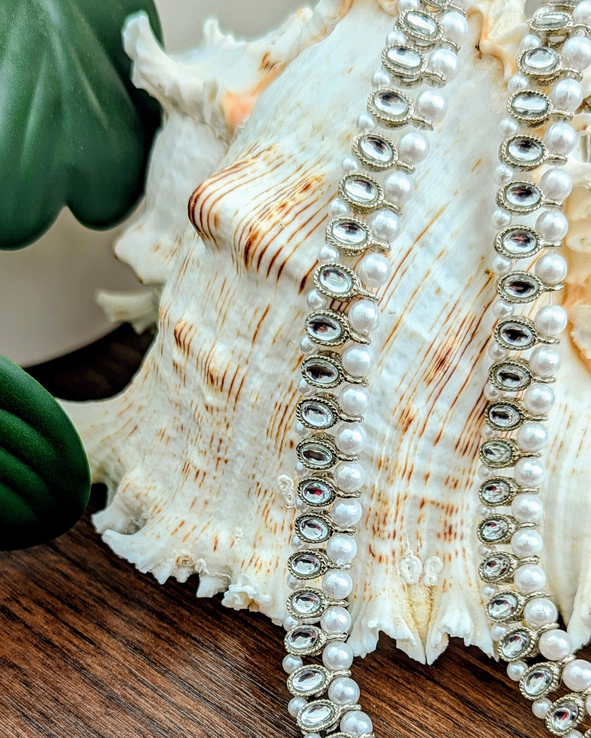 A pair of silver and pearl anklets with zircon stones displayed on a white seashell. Imitation jewelry. Pick-up in Ajax Ontario. Worldwide shipping available. Perfect for weddings, festival jewelry, indian Jewelry, kids jewelry, kundan jewelry, gifting, costume jewelry, fashion jewelry, Eid, onam, Diwali, karwachauth, navratri. Free shipping available. Jewelry for women. Indian jewelry in ajax durham toronto.