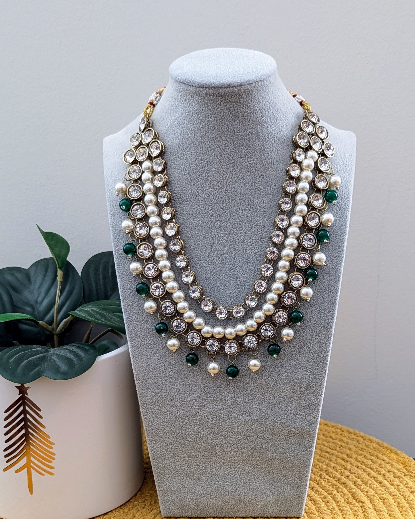 A pearl white Kundan necklace with multiple layers and green-tone metal beads displayed on a mannequin bust. Imitation jewelry. Pick-up in Ajax Ontario. Worldwide shipping available. Perfect for weddings, festival jewelry, indian Jewelry, kids jewelry, kundan jewelry, gifting, costume jewelry, fashion jewelry, Eid, onam, Diwali, karwachauth, navratri. Free shipping available. Jewelry for women. Indian jewelry in durham Toronto.