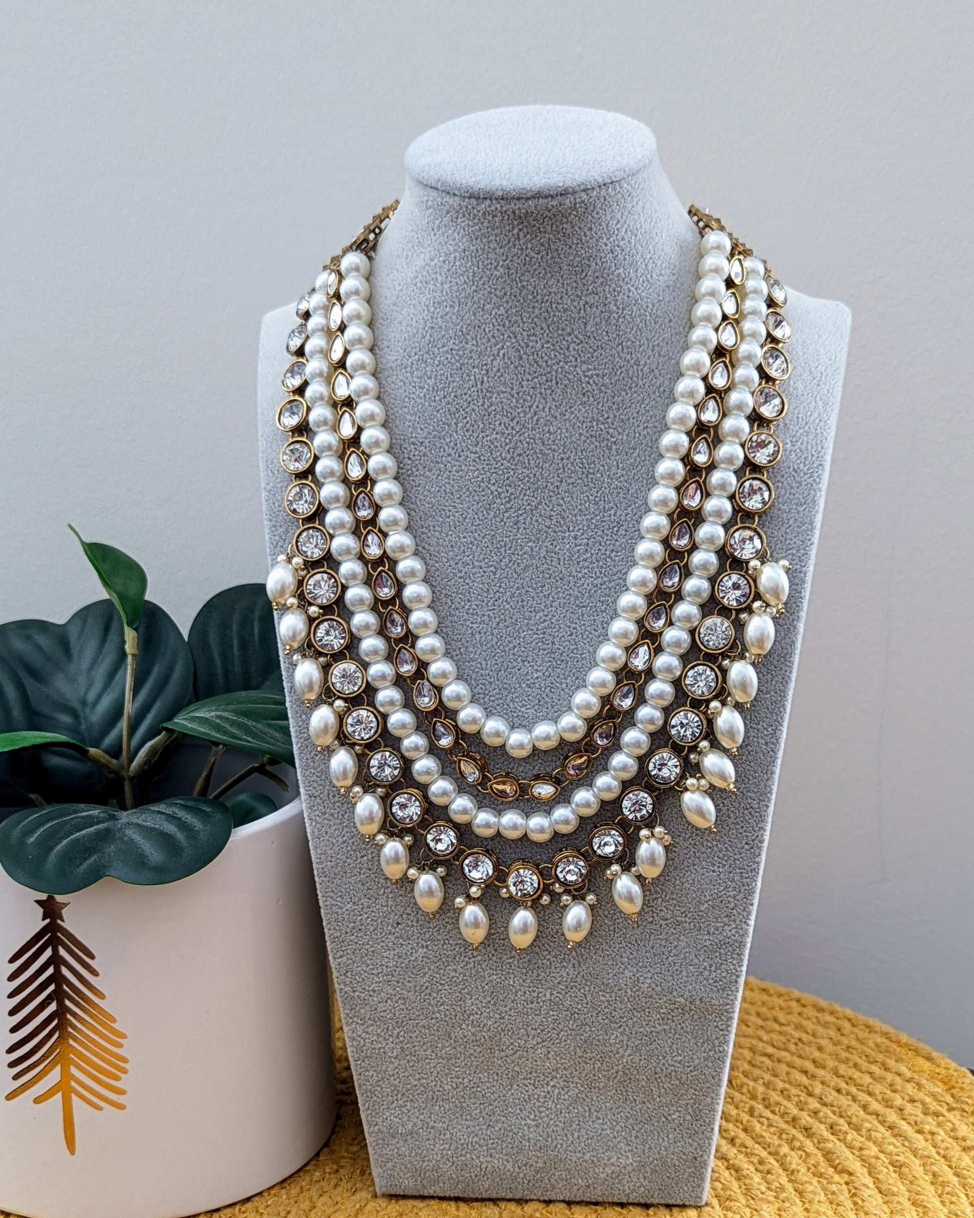A pearl white Kundan necklace with multiple layers and gold-tone metal beads displayed on a mannequin bust. Imitation jewelry. Pick-up in Ajax Ontario. Worldwide shipping available. Perfect for weddings, festival jewelry, indian Jewelry, kids jewelry, kundan jewelry, gifting, costume jewelry, fashion jewelry, Eid, onam, Diwali, karwachauth, navratri. Free shipping available. Jewelry for women. Indian jewelry in durham Toronto