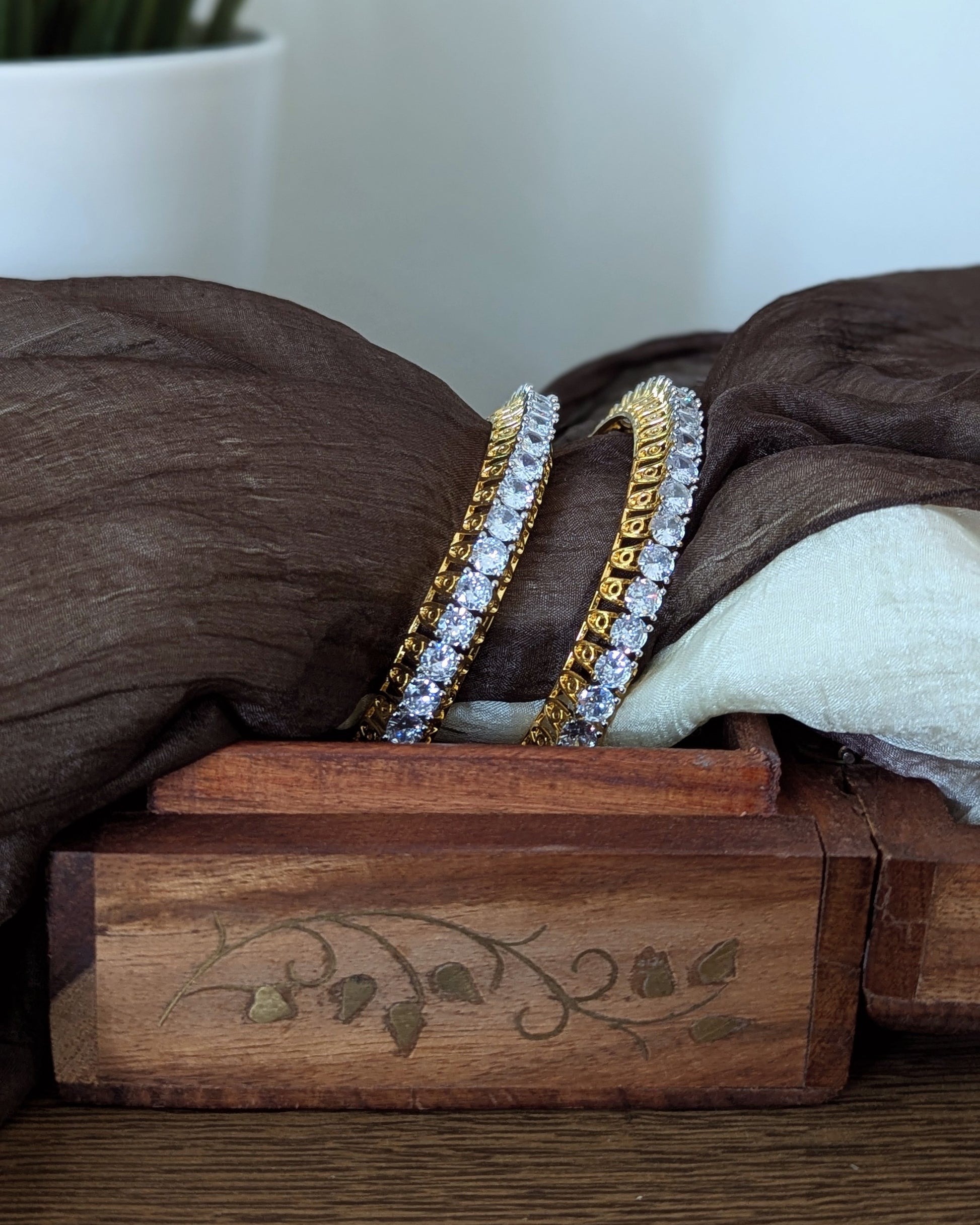 Gold bangles with diamond accents in a wooden box on a wooden surface. Imitation jewelry. Pick-up in Ajax Ontario. Worldwide shipping available. Perfect for weddings, festival jewelry, indian Jewelry, kids jewelry, kundan jewelry, gifting, costume jewelry, fashion jewelry, Eid, onam, Diwali, karwachauth, navratri. Free shipping available. Jewelry for women. Indian jewelry in ajax durham region. Bollywood style jewelry.