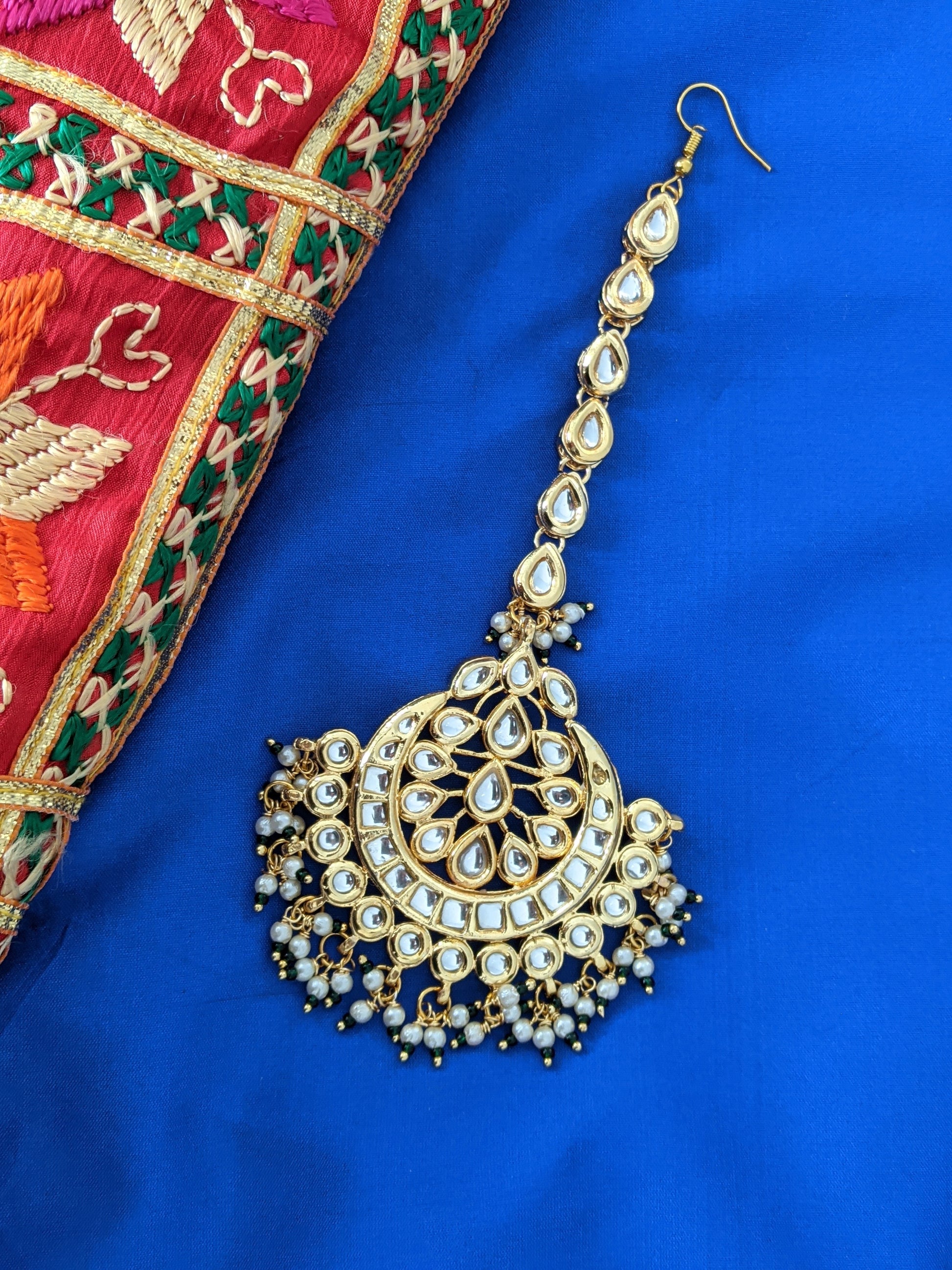 This Maang Tikka has been hand crafted intricately just like the Phulkari next to it. Phulkari is worldwide famous thread work done by finest Punjabi artisans.