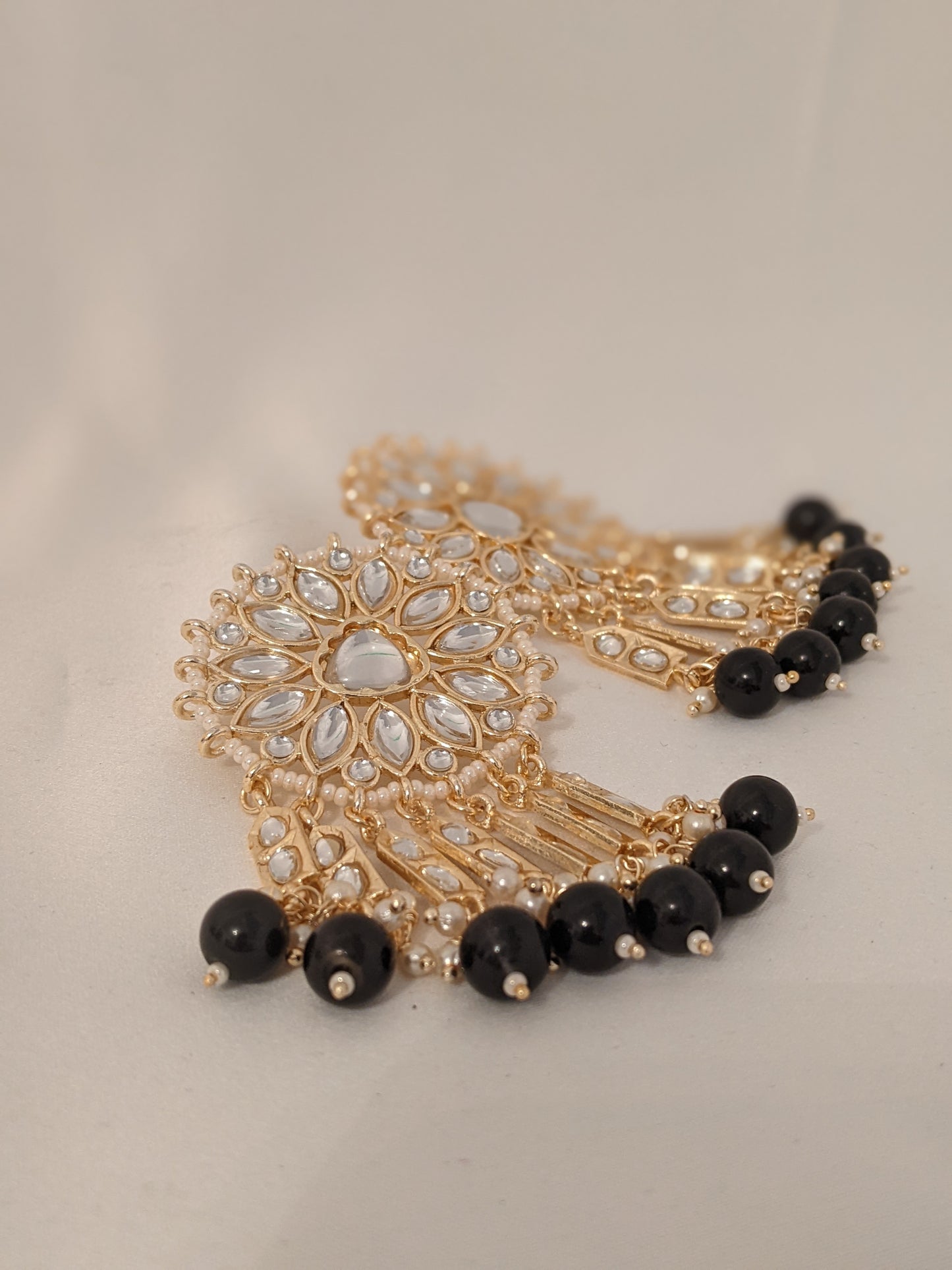 These beautiful earrings speak for themselves. Meticulously handcrafted in Kundan with dangling black pearl drops.