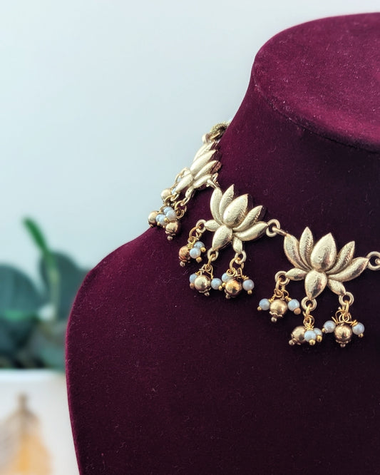 A gold-colored necklace with lotus flower designs displayed on a red velvet mannequin. Imitation jewelry. Pick-up in Ajax Ontario. Worldwide shipping available. Perfect for weddings, festival jewelry, indian Jewelry, kids jewelry, kundan jewelry, gifting, costume jewelry, fashion jewelry, Eid, onam, Diwali, karwachauth, navratri. Free shipping available. Jewelry for women. Indian jewelry in ajax durham region.