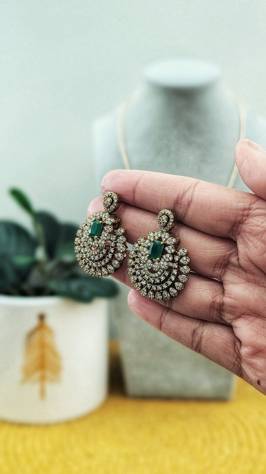 Traditional Indian statement necklace featuring an antique gold finish with a circular filigree pendant and emerald green center stone, displayed on a grey velvet bust next to a festive white planter. Gold and green Kundan earrings, chandbali style. Imitation jewelry. Pick-up in Ajax Ontario. Worldwide shipping available. Perfect for weddings, festival jewelry, indian Jewelry, kids jewelry, kundan jewelry, gifting, costume jewelry, fashion jewelry, Eid, onam, Diwali, karwachauth, navratri.