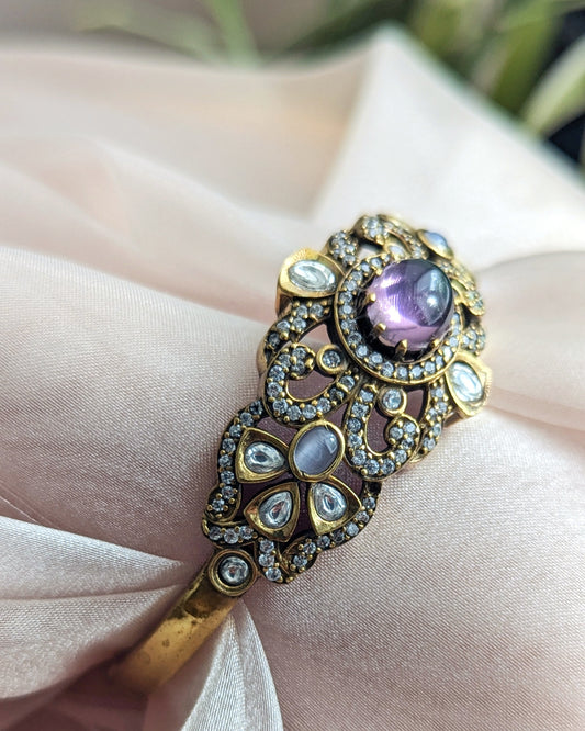 Single Bangle with purple gemstone and gold accents on a soft fabric background. Pick-up in Ajax Ontario. Worldwide shipping available. Perfect for wedding, festival jewelry, indian Jewelry, kids jewelry, kundan jewelry, gifting, costume jewelry, fashion jewelry, Eid, onam, Diwali, karwachauth, navratri. Free shipping available. Jewelry for women. Indian jewelry in ajax durham region. Bollywood style jewelry.