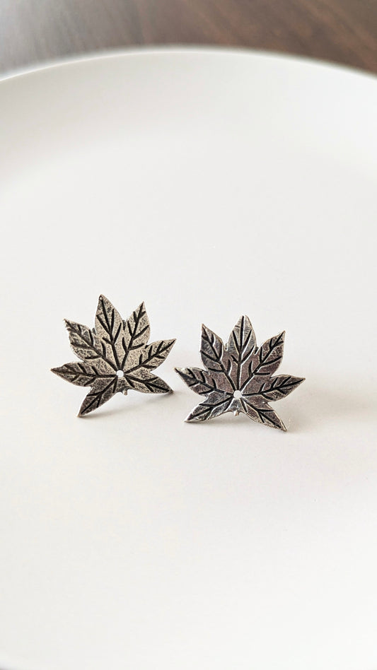 A pair of oxidized silver stud earrings designed to resemble maple leaves. Pick-up in Ajax Ontario. Worldwide shipping available. Perfect for wedding, festival jewelry, indian Jewelry, kids jewelry, kundan jewelry, gifting, costume jewelry, fashion jewelry, Eid, onam, Diwali, karwachauth, navratri. Free shipping available. Jewelry for women. Indian jewelry in ajax durham region.