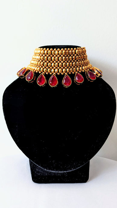 Traditional golden choker with Ruby lookalike red drop stones. Comes with dainty jhumkis.