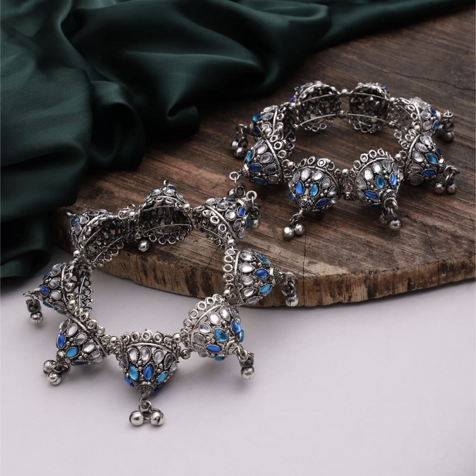 Bring a vibrant and unique look to any outfit with this oxidized silver Banjara Bangle! Made with a touch of dazzling blue stones, this bangle is sure to add a fun and eye-catching pop to your outfit